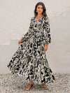 Woman wearing a black and white floral maxi dress with tie neckline, smocked waist, and tiered design, perfect for casual and formal occasions.

