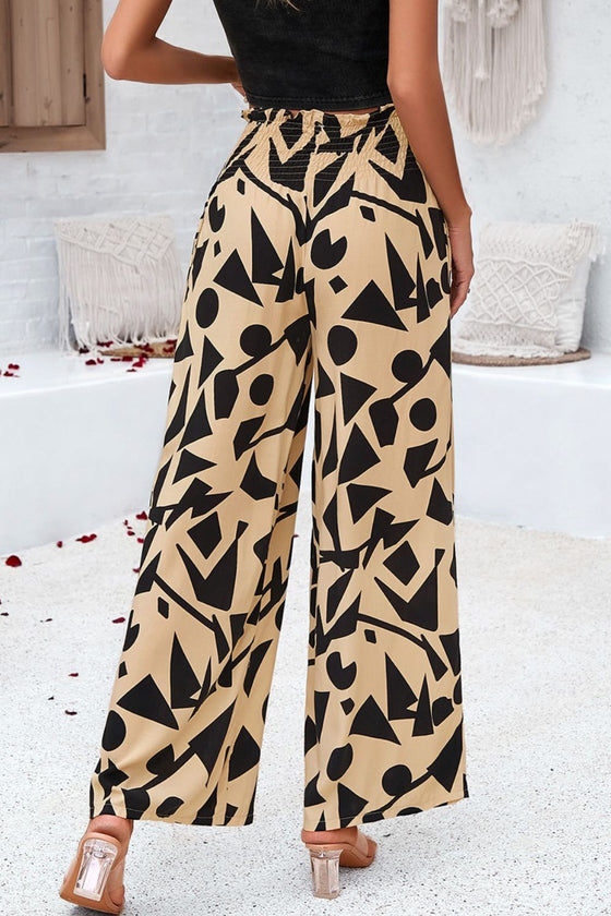 Back side woman wearing smocked printed wide-leg pants with pockets in a bold, artistic pattern, perfect for casual and vacation wear.