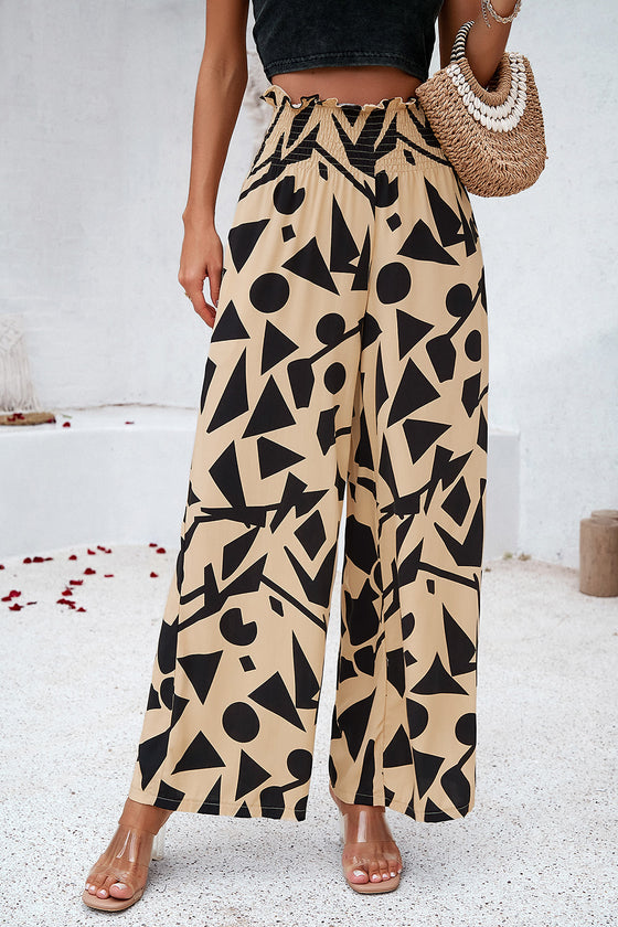 Woman in beige Smocked Printed Wide Leg Pants with artistic black print, featuring side pockets and a smocked waistband.