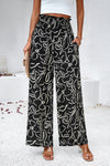 Woman in black Smocked Printed Wide Leg Pants with a modern print, designed with a comfortable smocked waistband.