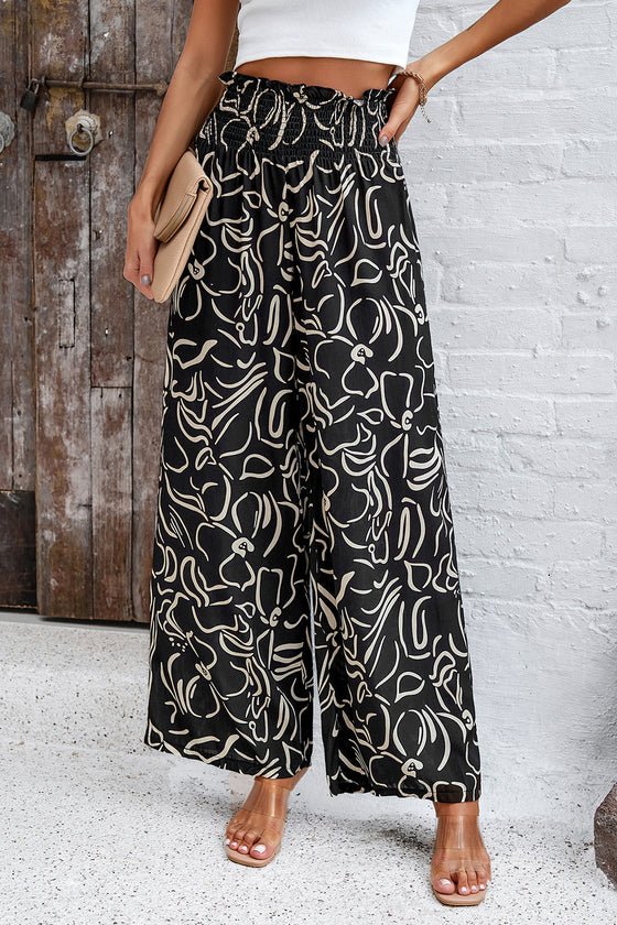 Woman in black Smocked Printed Wide Leg Pants with a modern print, designed with a comfortable smocked waistband.