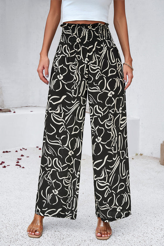 Woman in black Smocked Printed Wide Leg Pants with a modern print, designed with a comfortable smocked waistband.