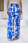 Back woman wearing Smocked Printed Wide Leg Pants in blue, showing off the wide-leg fit and smocked waist detail.