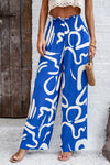 Side view Woman wearing Smocked Printed Wide Leg Pants in blue, showing off the wide-leg fit and smocked waist detail.