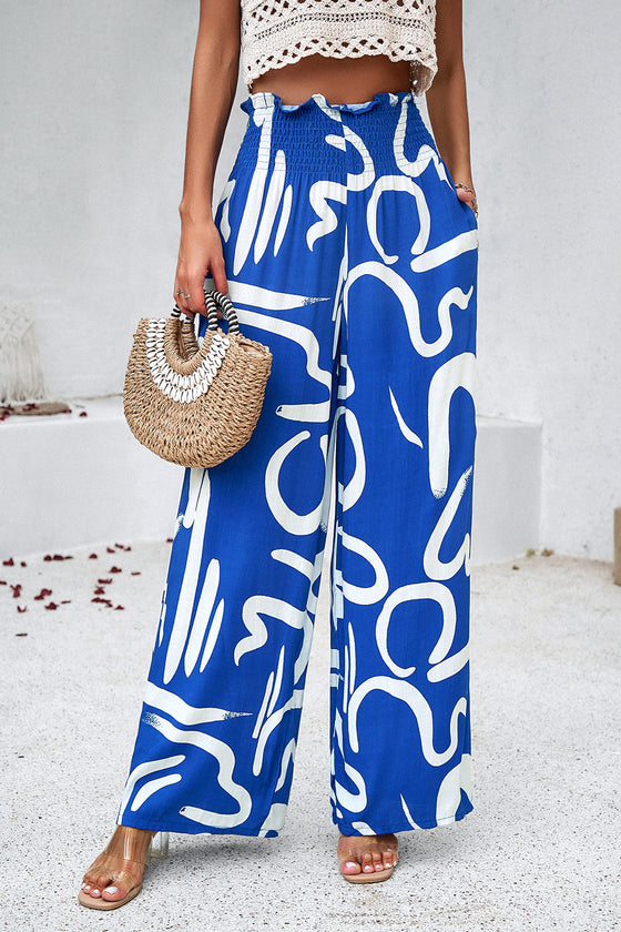 Woman wearing Smocked Printed Wide Leg Pants in blue, showing off the wide-leg fit and smocked waist detail.