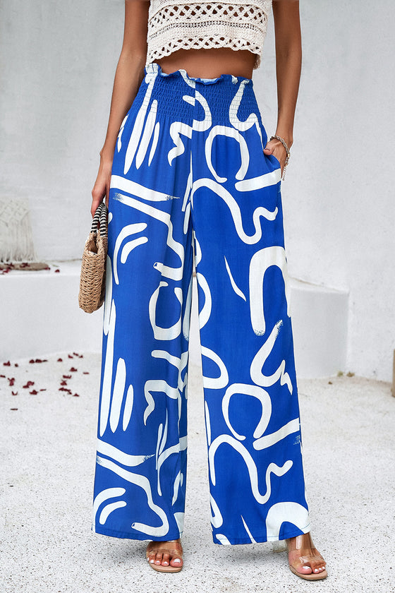 Woman wearing Smocked Printed Wide Leg Pants in blue, showing off the wide-leg fit and smocked waist detail.