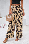 Front side woman wearing smocked printed wide-leg pants with pockets in a bold, artistic pattern, perfect for casual and vacation wear.