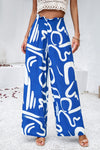 Main view woman wearing smocked printed wide-leg pants with pockets in a bold, artistic pattern, perfect for casual and vacation wear.