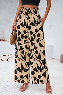  Woman wearing smocked printed wide-leg pants with pockets in a bold, artistic pattern, perfect for casual and vacation wear.