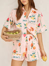  Model wearing a peach summer printed button down co-ord set featuring a short-sleeve top and matching flowy skirt, styled for a chic daytime look.