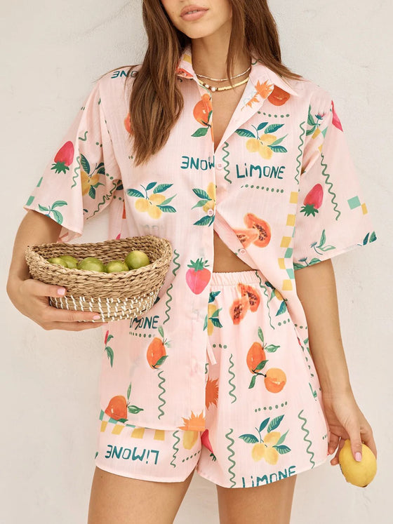  Model wearing a peach summer printed button down co-ord set featuring a short-sleeve top and matching flowy skirt, styled for a chic daytime look.