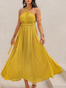  Woman wearing a vibrant yellow Swiss Dot Backless Sleeveless Maxi Dress with a halter neckline and braided waist belt, perfect for summer occasions.