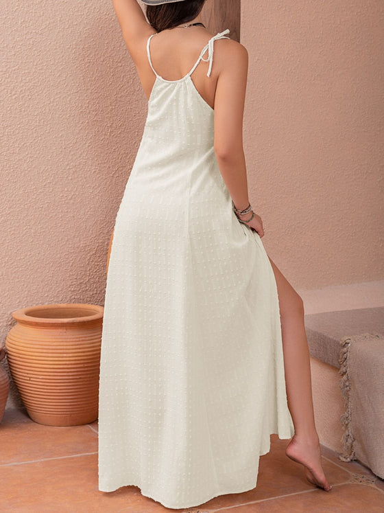 A woman wearing a Swiss Dot Cutout Sleeveless Maxi Dress in a soft white color, styled with statement jewelry, perfect for summer occasions.