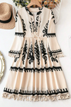 Front view of the Tassel Printed Mini Dress with boho tassels, tied neckline, and intricate black-and-white design.