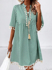  Model wearing a green mini dress with a geometric print, tassel details, and a notched neckline.