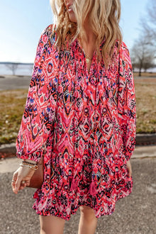  A vibrant printed long sleeve mini dress with a tassel tie neck, styled in bold pink and multi-tones, perfect for casual outings and chic gatherings.