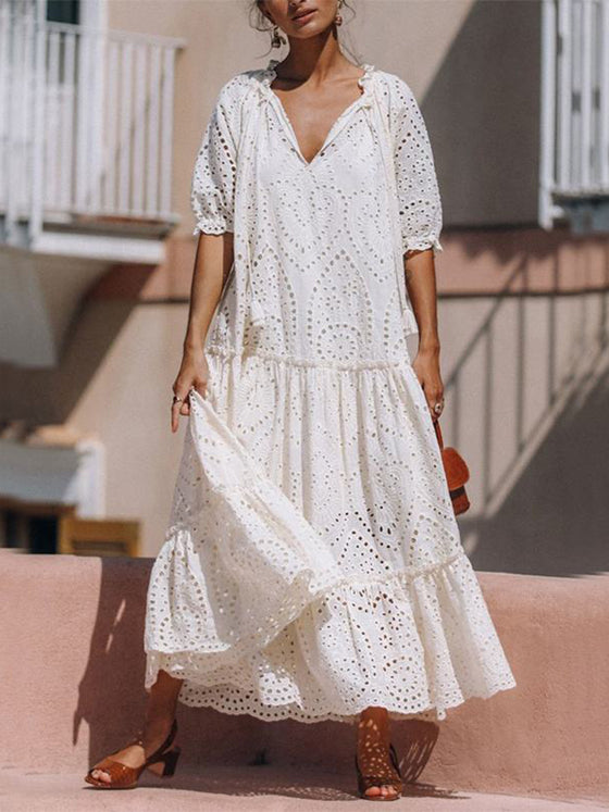 Woman wearing the Tie Neck Half Sleeve Tiered Dress, paired with a stylish bag and sandals for a chic daytime look.
