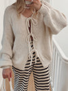 Front view of the Tied Long Sleeve Dropped Shoulder Cardigan in neutral beige, styled with casual striped pants.