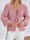 Woman wearing the cardigan in a cozy indoor setting, showcasing the tie closures and soft knit fabric.