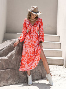  Woman wearing a vibrant Tied Cutout Printed Long Sleeve Midi Dress with floral patterns, tie-front detail, and elegant flowy silhouette.