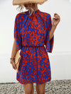 Front view of the Tied Printed Mock Neck Mini Dress with bold red and blue patterns and elastic waist.