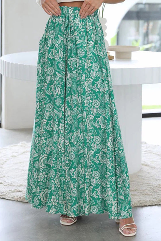 Woman wearing Tied Wide Leg Pants in green with a floral print, featuring a tie-waist and wide-leg design.