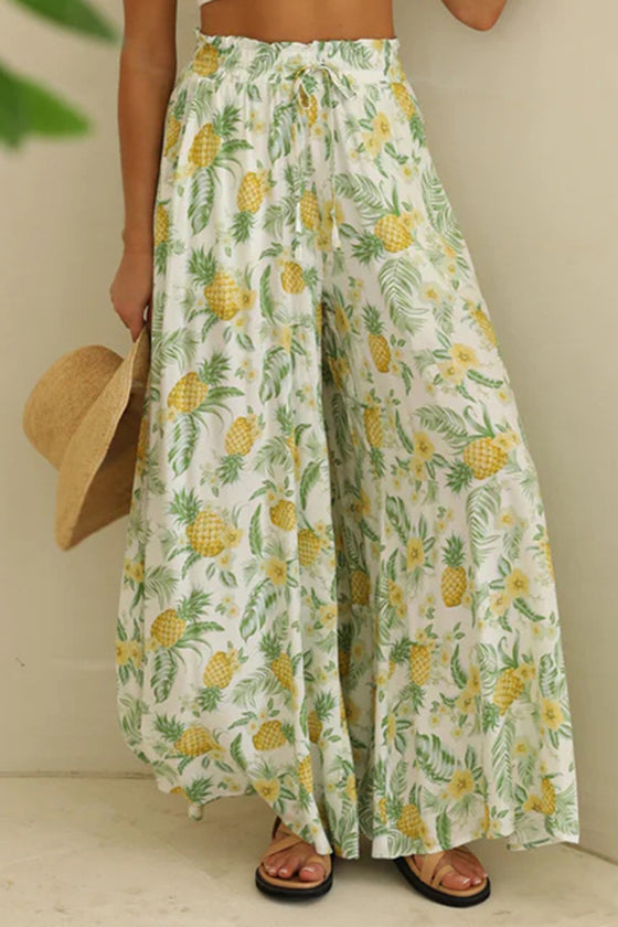 Woman wearing Tied Wide Leg Pants in green with a floral print, featuring a tie-waist and wide-leg design.