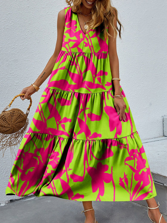 Woman wearing a vibrant Tiered Printed V-Neck Sleeveless Dress with colorful paisley-inspired print, accessorized with a straw bag and sandals.