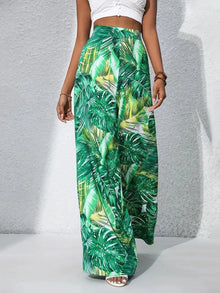  Model showcasing the green high waist pants from the front, featuring a bold tropical print and dramatic wide-leg flow, ideal for vacation vibes.

