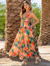 Woman wearing a Twisted Printed V-Neck Cami Dress featuring a bold floral print in orange and purple, with a maxi length and flattering silhouette.

