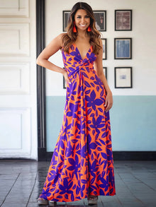  Woman wearing a Twisted Printed V-Neck Cami Dress featuring a bold floral print in orange and purple, with a maxi length and flattering silhouette.

