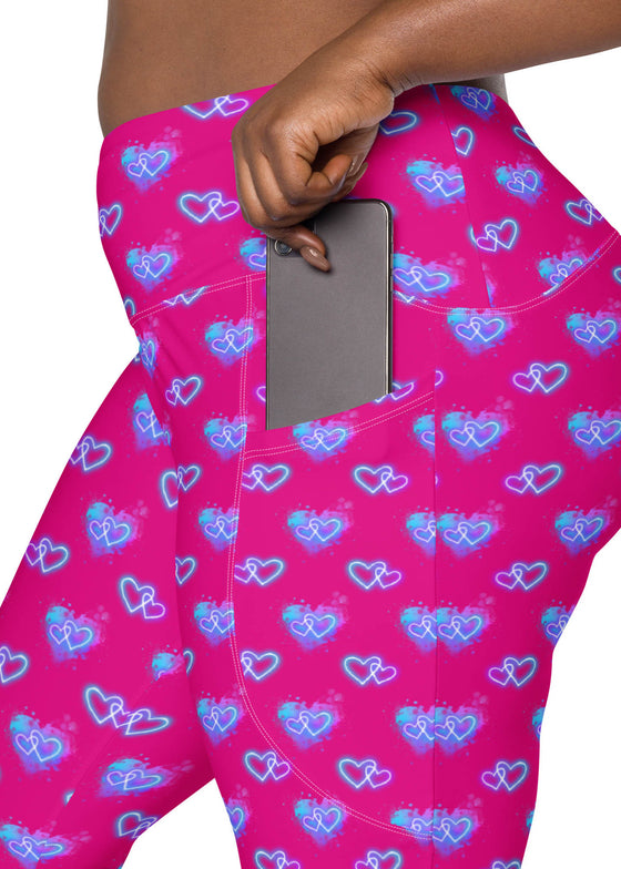 Plus-size woman showcasing the pocket design of Vibrant Neon Heart violet-red high-waisted leggings. Functional and stylish gym leggings for women with high-rise compression, bold neon heart print, and pockets.