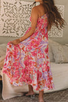 Back view of the dress showing the open one-shoulder back design and long fluid hemline in bright floral print.


