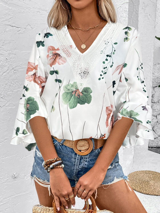 White blouse featuring elegant floral patterns and half-length sleeves, worn front-facing with a tucked-in look.