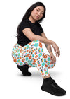 Model sitting wearing white floral high waisted leggings with side pockets, showing a comfortable, supportive fit and floral design for active or casual wear.