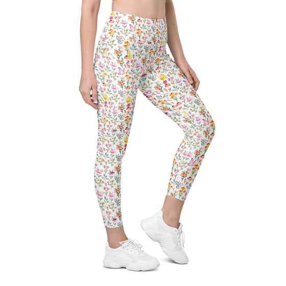 Model wearing high waisted white leggings with floral, bee, and butterfly print. Compression leggings for women with pockets, perfect for gym or yoga.