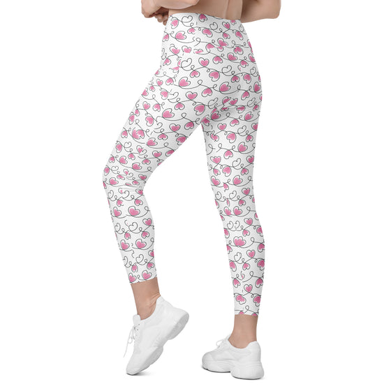 Model walking in white leggings with never ending hearts pattern. Gym-ready compression leggings for women with pockets and sculpting fit.
