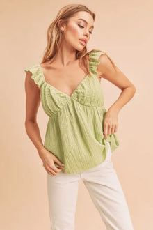  Woman wearing a yellow-green ruffled strap top with gathered neckline, styled in a full front view for a chic summer look.