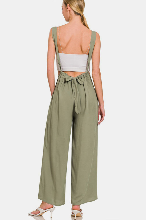 Model wearing Zenana Pocketed Wide Strap Wide Leg Overalls in olive green, styled with a white crop top and heels for a casual chic look.

