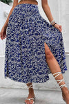 Model wearing a ditsy floral high waist skirt with a side slit, styled with strappy sandals for a summery look.