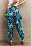 Back view of tropical print long pants with a comfortable, high-rise smocked waistband and vibrant botanical pattern.